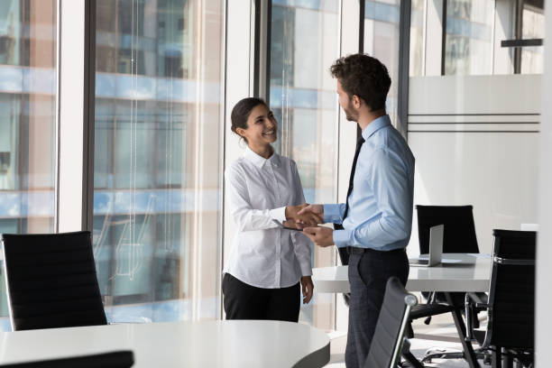 Two diverse confident business man and woman shaking hands stock photo