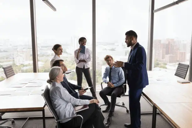 Photo of Happy engaged Indian business leader motivating diverse staff for work