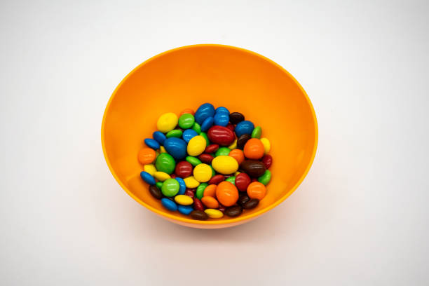 istock Rainbow Colored Candy Coated Chocolate Buttons in a orange bowl isolated on White 1398760509