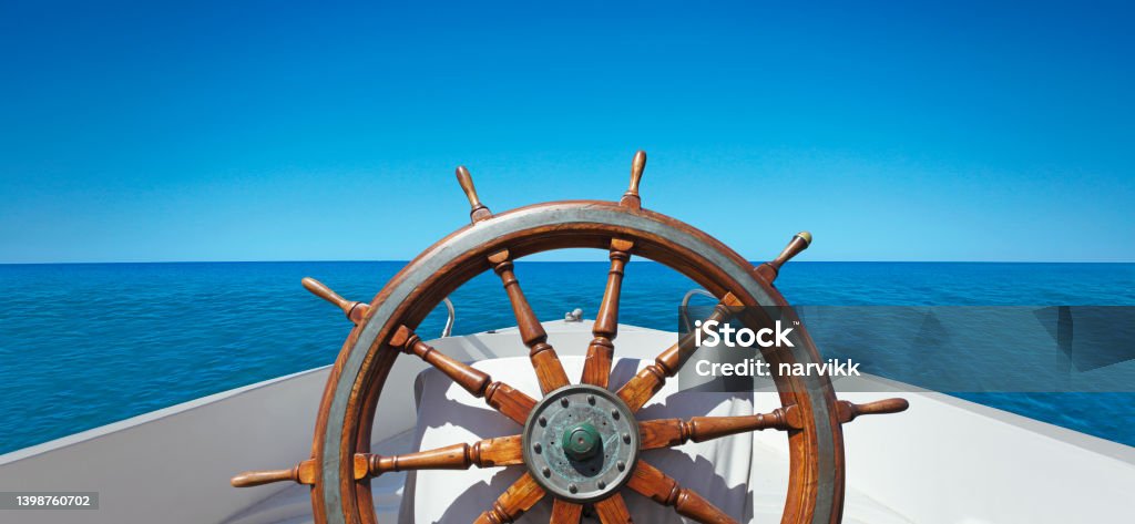Ship's wheel on the sea Panoramic view of wooden ship's wheel on the boat at the ocean Sailboat Stock Photo