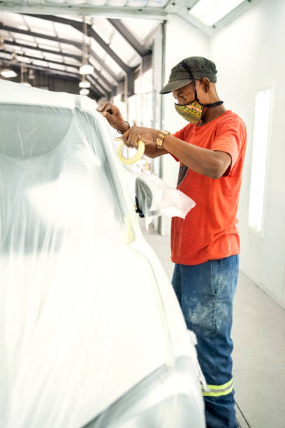 man in auto repair shop preparing car parts for painting - paint preparation adhesive tape indoors imagens e fotografias de stock