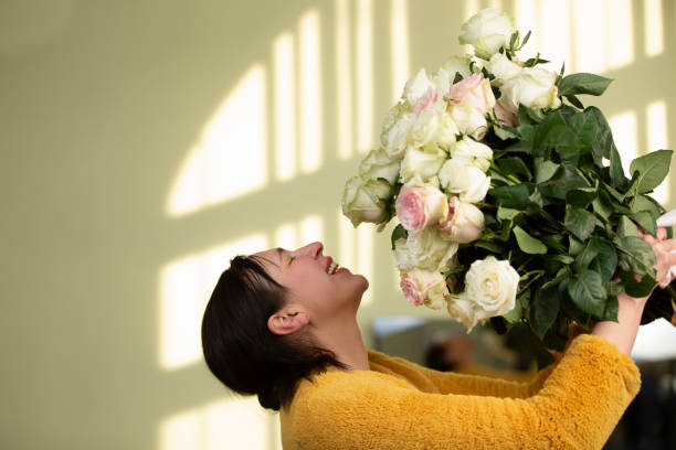 une femme heureuse d’âge moyen avec un énorme bouquet de roses se réjouit. femme cinquante ans. - 45 49 years photos et images de collection