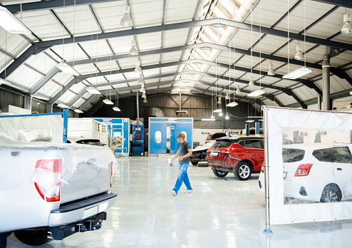 Inside of an auto repair shop with many cars and working walking