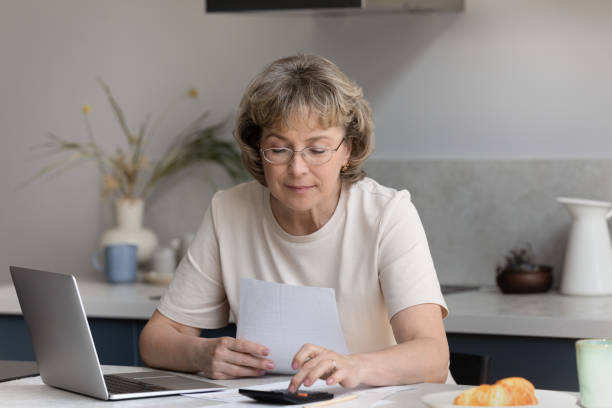 istock Focused middle aged woman calculating bills at home. 1398764328