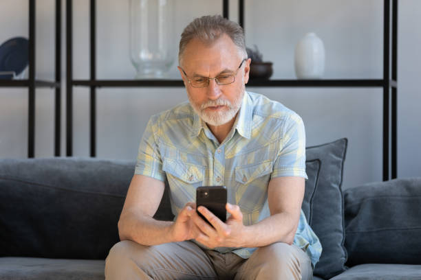 istock Concentrated old retired man using cellphone at home. 1398764348