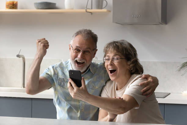 istock Overjoyed senior couple celebrating mobile internet success. 1398765547
