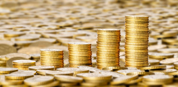 Golden coins stacks surrounded by a big group of coins stock photo
