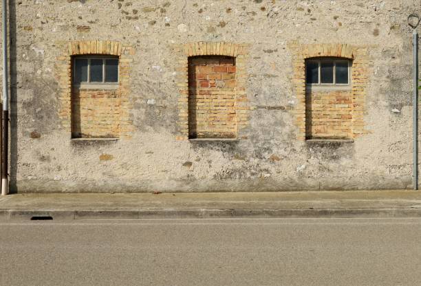 istock Grunge concrete wall and windows walled with bricks. Cement sidewalk and asphalt road in front. 1398767061