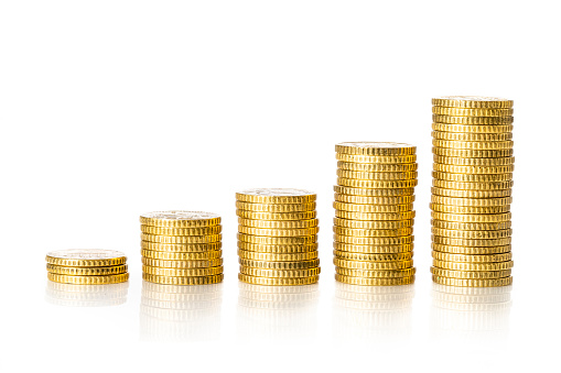 Front view of a group of stacks of golden coins arranged side by side in ascending height order isolated on a white background.