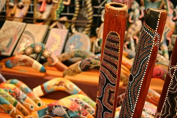 Didgeridoos on background of blurred aboriginal souvenirs, including boomerangs.