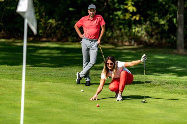 ゴルフをする夫婦、緑を読む若い女性、パットの準備をする - golf golf course putting men ストックフォトと画像