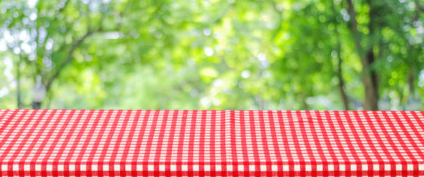istock Empty table with red and white tablecloth over blurred park nature background, for product display montage, spring and summer 1398772529