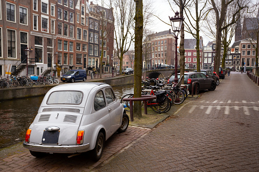 streets of amsterdam. vintage car in the foreground. houses and lot of bikes\