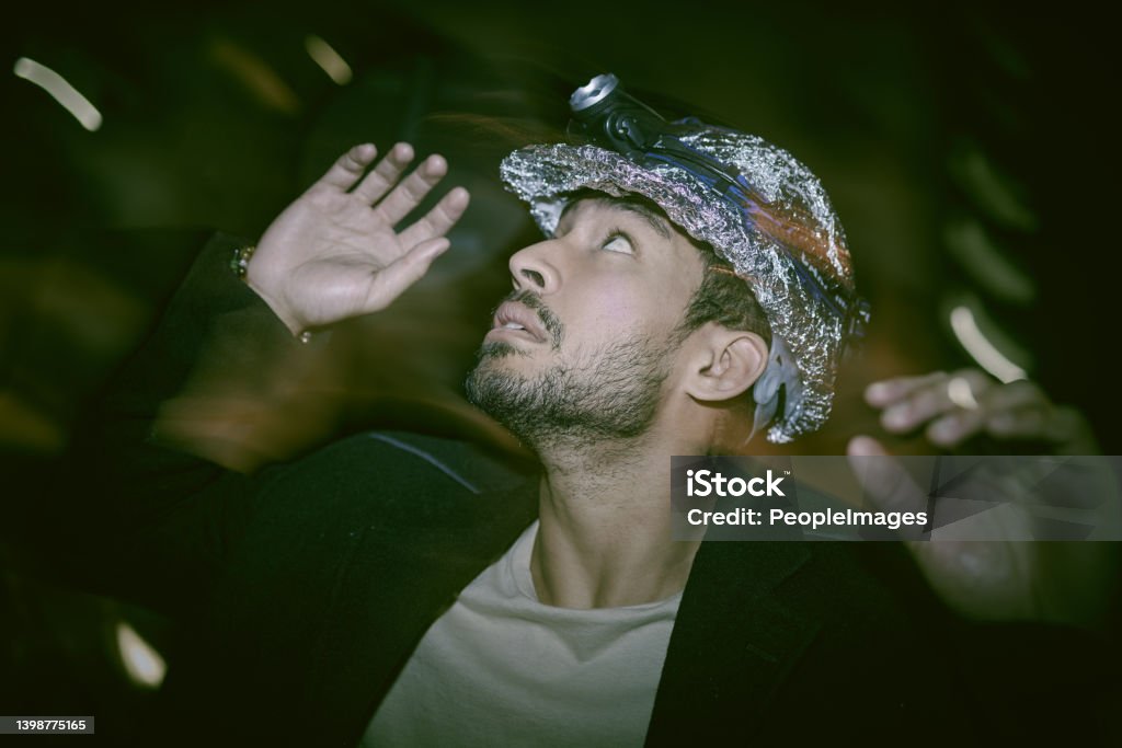 Asian man with mental disorder walking alone at night and feeling paranoid wearing a helmet covered with foil. Mixed race man mentally ill, feeling depressed and walking outside. Insomniac feeling scared and hopeless Paranoia Stock Photo