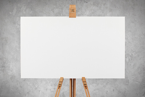 A blank canvas board on a wooden artist's easel against a concrete wall background