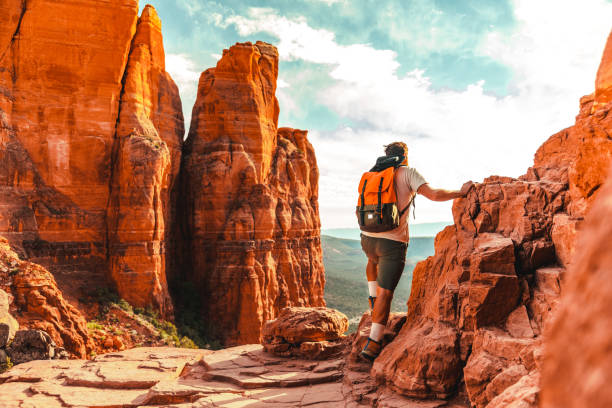 istock Adventurous man with a backpack on his back climbs a rock 1398775835