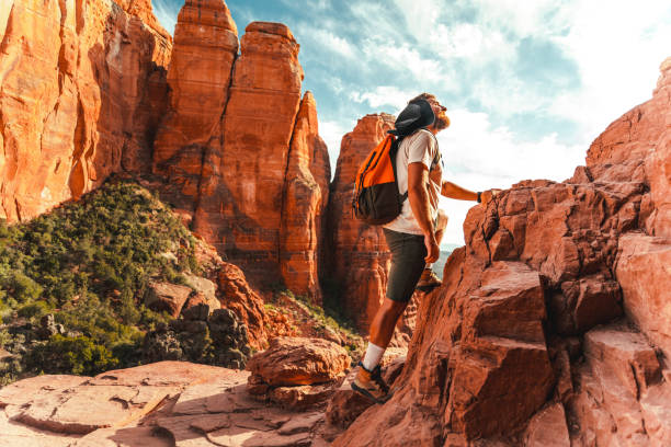 istock Adventurous man with a backpack on his back climbs a rock and looking up 1398775901