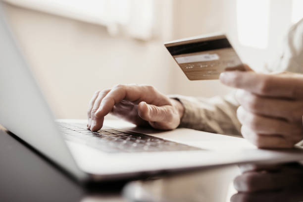 istock Payment online. Young man using laptop with credit card at home 1398775906