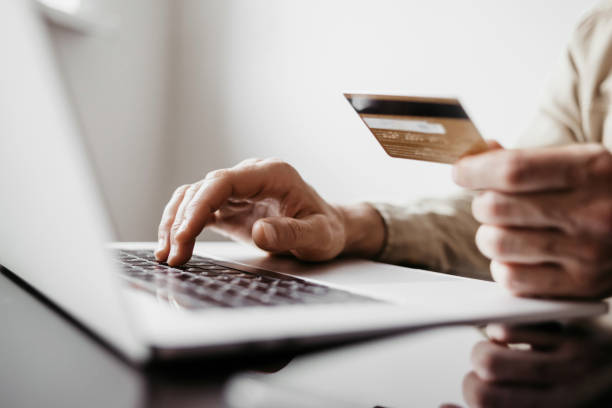 istock Payment online. Young man using laptop with credit card at home 1398775907