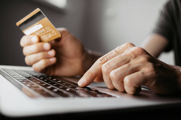 istock Payment online. Young man using laptop with credit card at home 1398775989