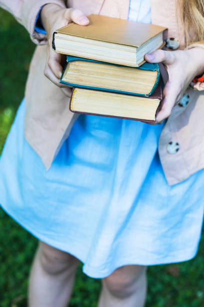 istock girl holding a stack of books in her hands 1398779858