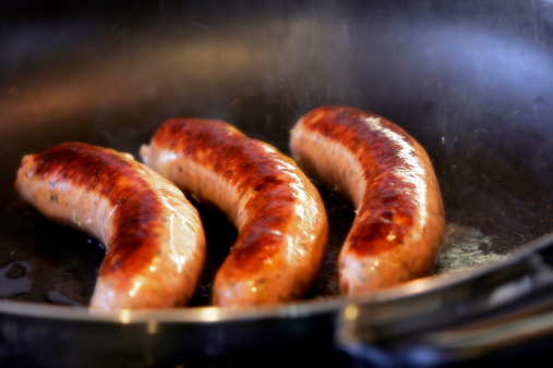 Close-up of sausages frying in a pan with oil spatter â?? can also be used for healthy alternative image as these are Turkey Sausages (shallow focus).