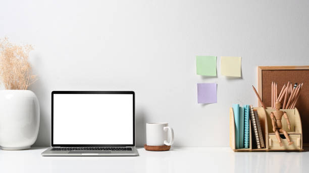 istock Creative designer workplace with laptop computer, flower pot, coffee cup and stationery on white table. 1398780991