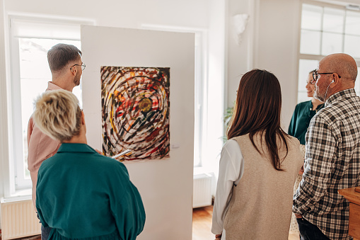 Four girl friends looking at modern painting in art gallery. Abstract painting