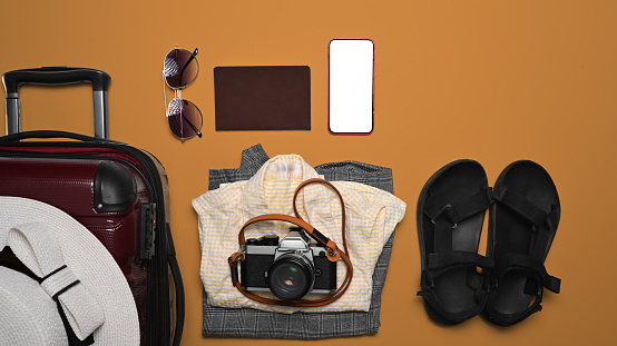 Suitcase with traveler accessories on white orange background. Packing for a new journey.