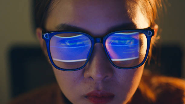 istock Close up of face of young Asian woman, developer programmer, software engineer, IT support, wearing glasses working hard at night overtime on computer to check coding in bugging system. 1398785087