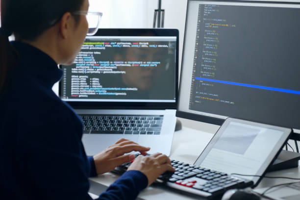 アジアの若い女性、開発者プログラマー、ソフトウェアエンジニア、itサポート、メガネをかけてコンピュータ上で作業し、盗聴システムでコーディングをチェックします。バックビュー - it技術者 ストックフォトと画像