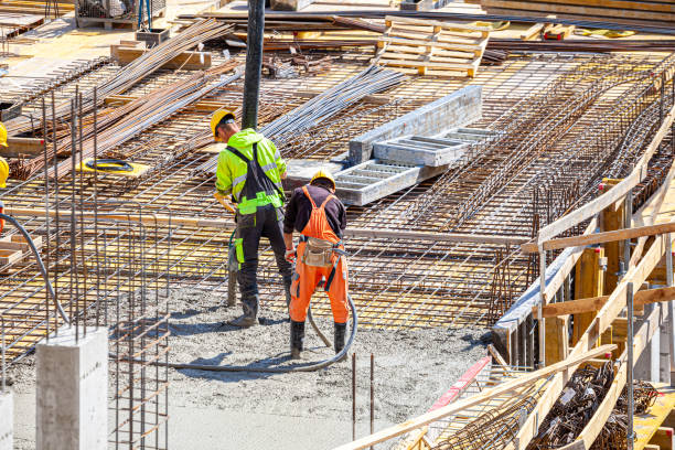 istock One worker pours concrete on the construction site and another worker vibrates the concrete. 1398785240