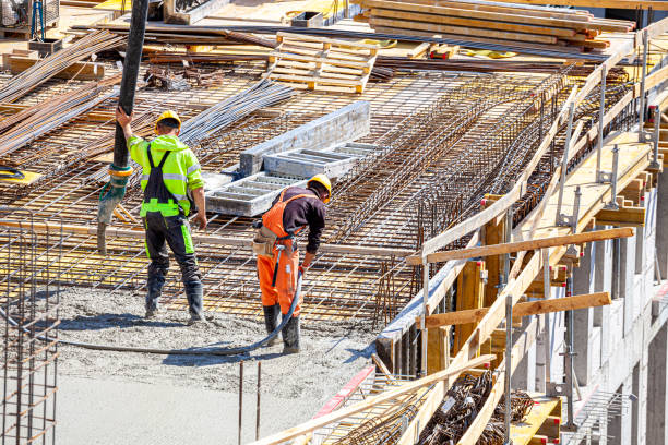 istock One worker pours concrete on the construction site and another worker vibrates the concrete. 1398785252