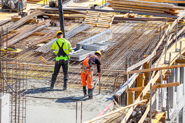 istock One worker pours concrete on the construction site and another worker vibrates the concrete. 1398785262