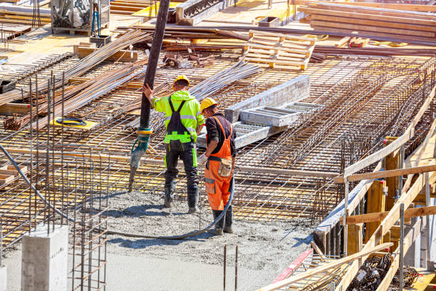 istock One worker pours concrete on the construction site and another worker vibrates the concrete. 1398785274