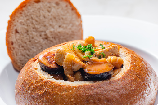 stew with pork meat, chickpeas and sausge in loaf of bread