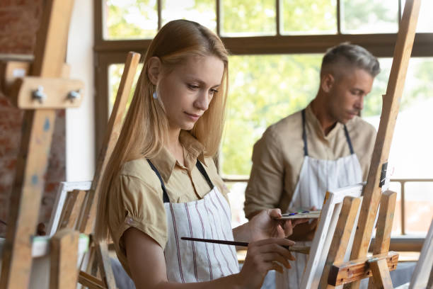 istock Young craft studio class student in apron drawing in paints 1398786618