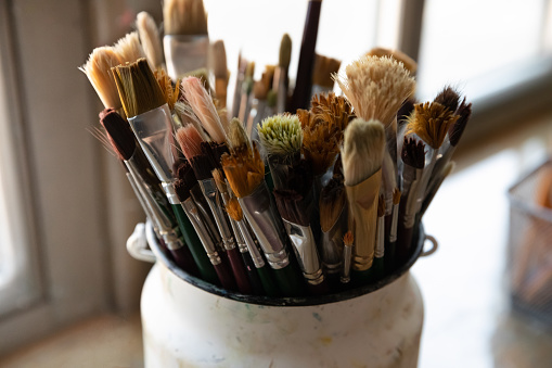 Bunch of paint brushes in metal bucket close up. Artist paintbrushes pack for drawing in oil, watercolors. Artistic tools for art school class, workshop, craft studio supplies