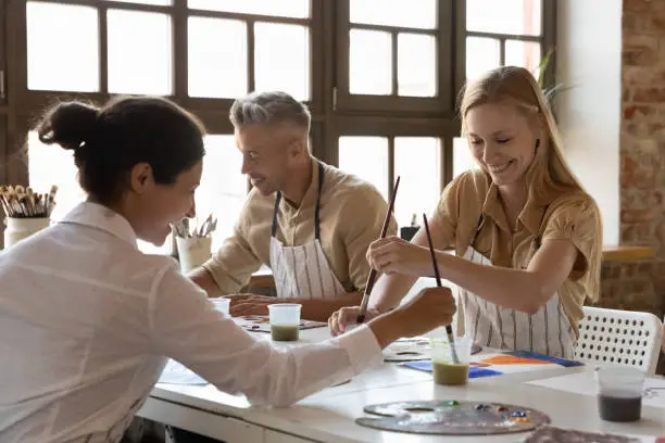 Photo of Cheerful diverse art school classmates girls talking on class