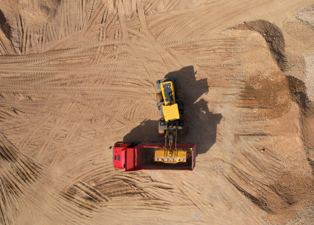istock Wheel loader load sand in dump truck in open pit. Front end loader on earthworks in open-pit mining. Heavy machinery on developing opencast. 1398787541