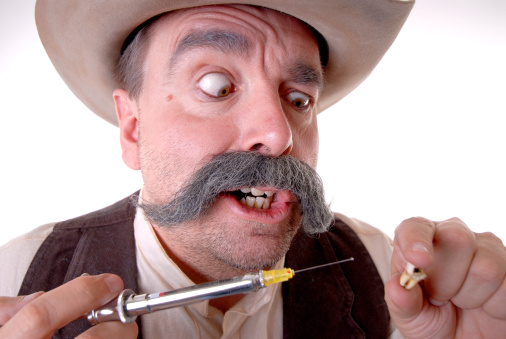 Old West Cowboy doing Dental Work - Holding a large metal syringe and molar / tooth.