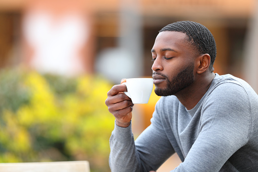 Man with black skin enjoying aroma of coffee cup