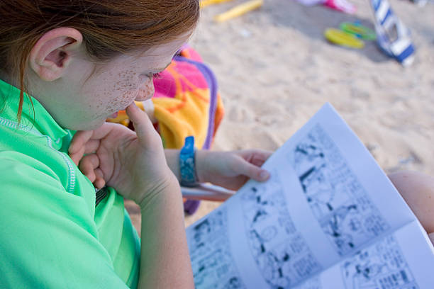 Child Reading on the Beach Child Reading book on the Beach reading comic book stock pictures, royalty-free photos & images