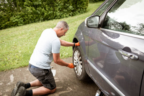 istock Middle aged man with grey hair changes tires on his car 1398791505