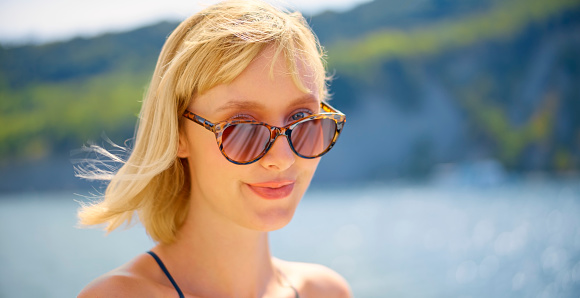 Close-up of young woman wearing sunglasses and smiling.