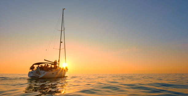 Large group of friends sailing and having fun on boat during sunset.