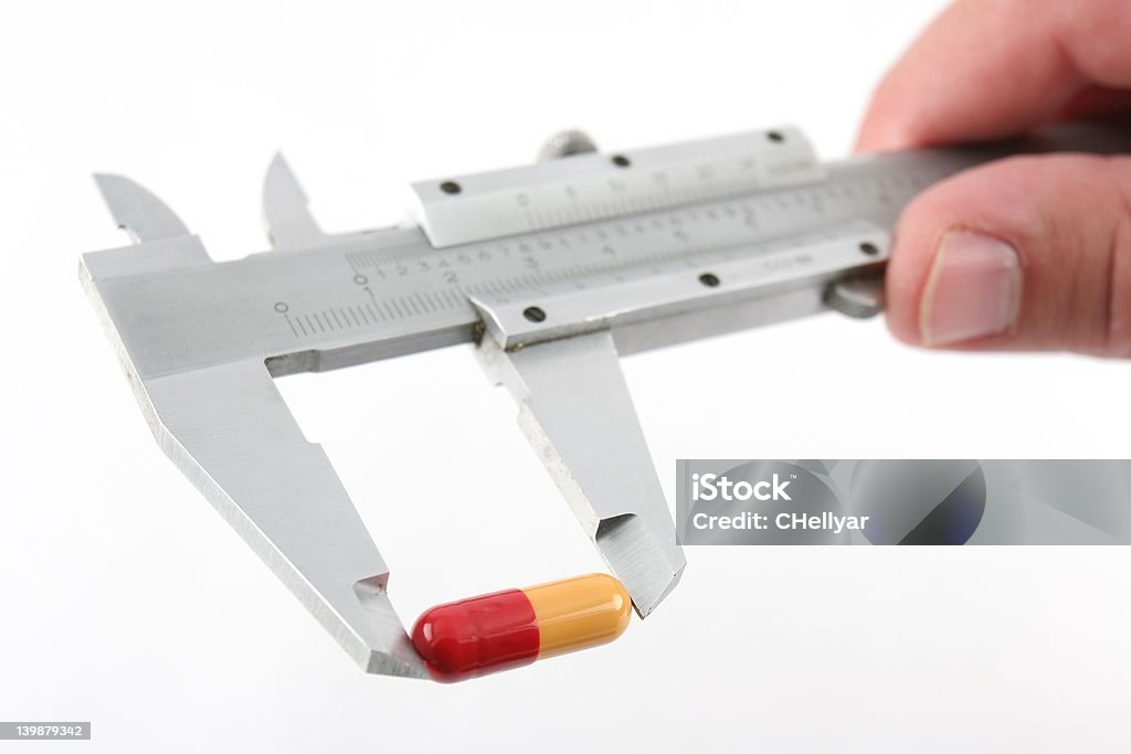 Measuring your dosage Measuring a drug capsule with a pair of callipers, shallow DOF, focus on one end of capsule. Addiction Stock Photo