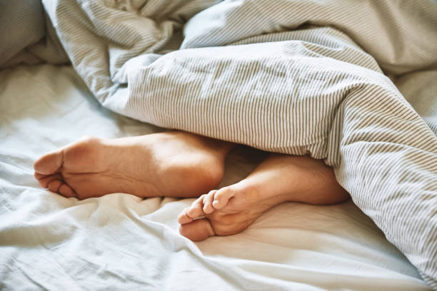 istock Female legs in the bed under blanket 1398796114