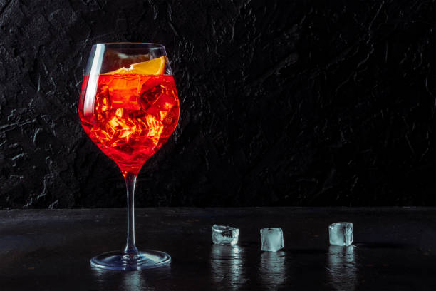 Aperol cocktail with a fresh orange and ice cubes, a side view on black stock photo
