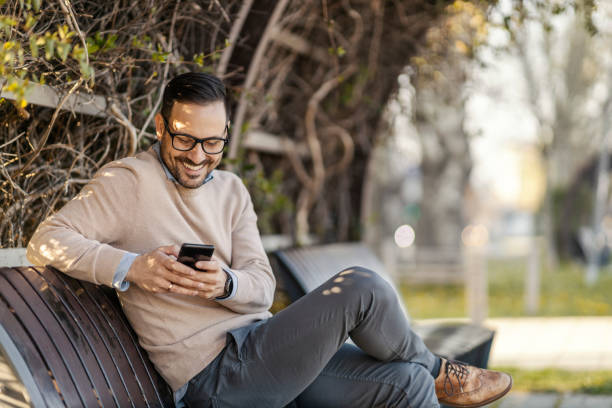 istock A happy man texting messages while sitting in a park. 1398799408